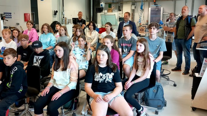 Clever-gebaut-Gewinner/innen besuchen NOI Techpark Schüler und Erwachsene sitzen und stehen in einem modernen Klassenzimmer bei einer Präsentation