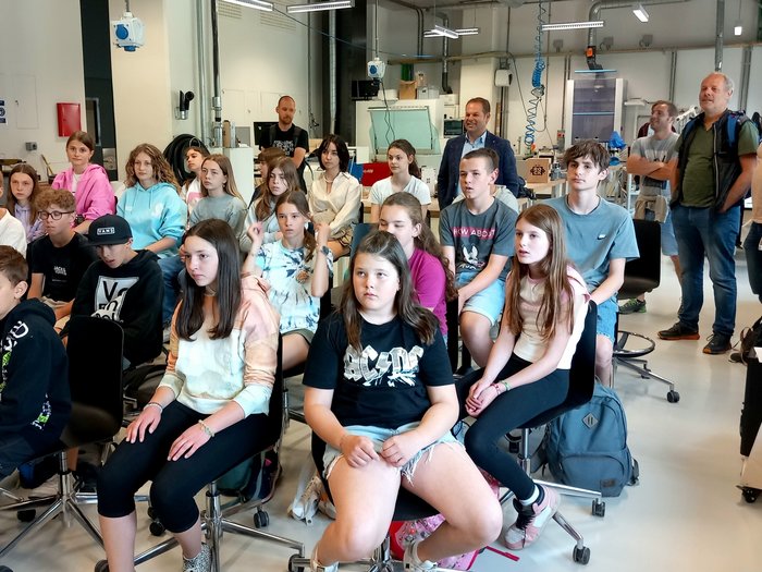 Clever-gebaut-Gewinner/innen besuchen NOI Techpark Schüler und Erwachsene sitzen und stehen in einem modernen Klassenzimmer bei einer Präsentation