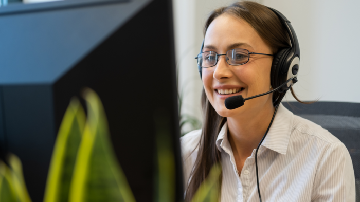 WIFO-Wirtschaftsbarometer Frühjahr 2024: gutes Geschäftsklima im Dienstleistungssektor, Ungewissheit im Güterverkehr Frau mit Brille und Headset arbeitet lächelnd am Computer