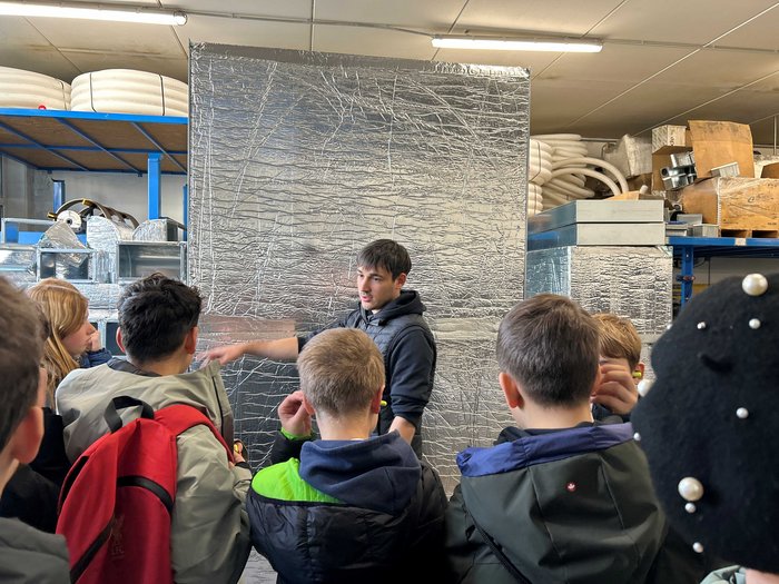 Handwerks- und Gastbetriebe im Fokus Mann erklärt Jugendlichen in Lagerhalle isolierte Metallstrukturen