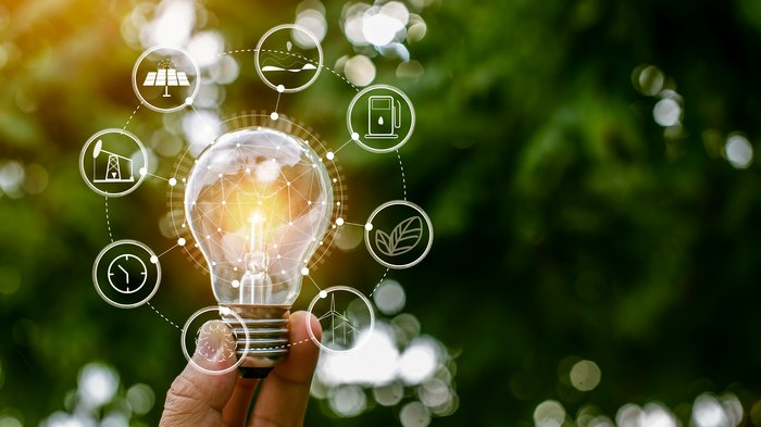 Wichtiges Signal: Energieförderungen 2024 Hand hält Glühbirne mit Symbolen für erneuerbare Energiequellen und Nachhaltigkeit
