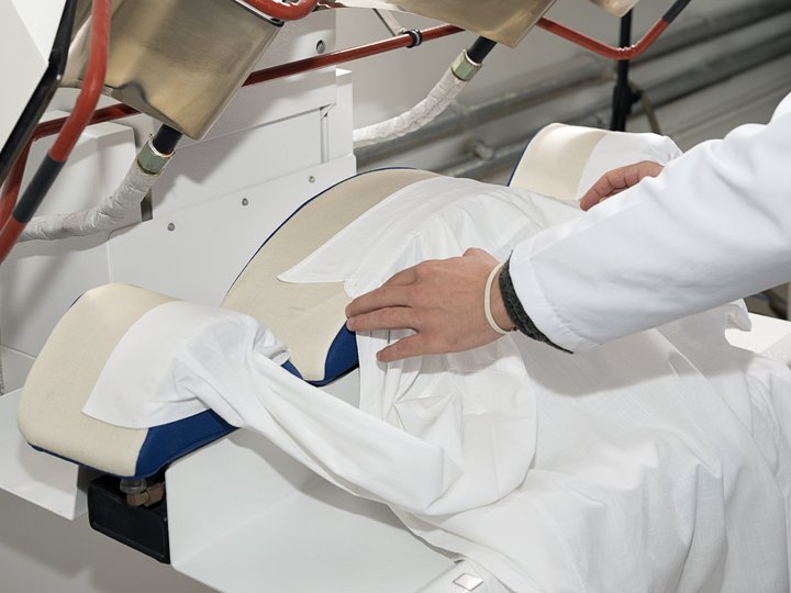 Pulitintori Persona posa una camicia bianca sulla macchina da stiro industriale