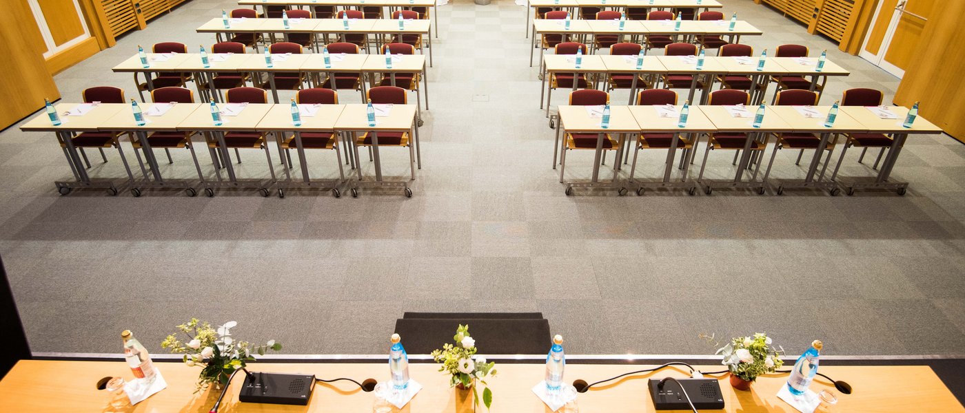 Affitto aule seminari Sala conferenze vuota con tavoli, sedie e bottiglie d'acqua preparata per riunione