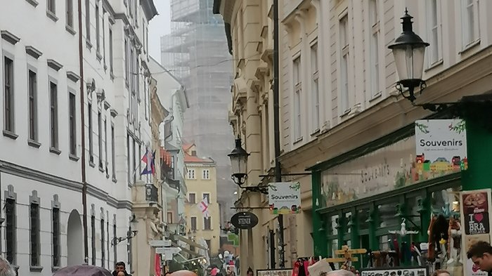 Auf Reisen: Althandwerker auf Flusskreuzfahrt Belebte Straße mit Souvenirläden und historischen Gebäuden