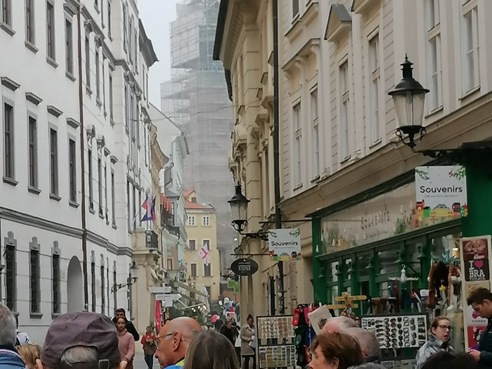 Auf Reisen: Althandwerker auf Flusskreuzfahrt Belebte Straße mit Souvenirläden und historischen Gebäuden