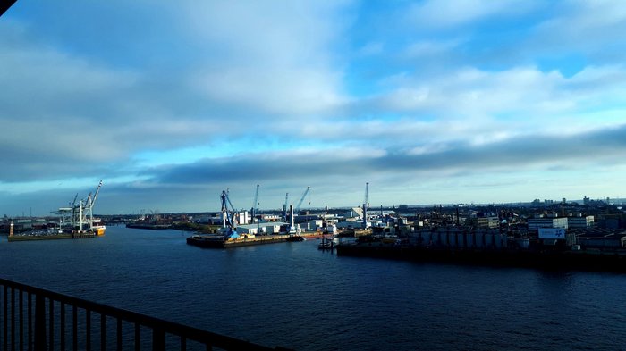 Die Althandwerker besuchen Hamburg Hafen mit Kränen, Lagerhäusern und Schiffen unter bewölktem blauen Himmel
