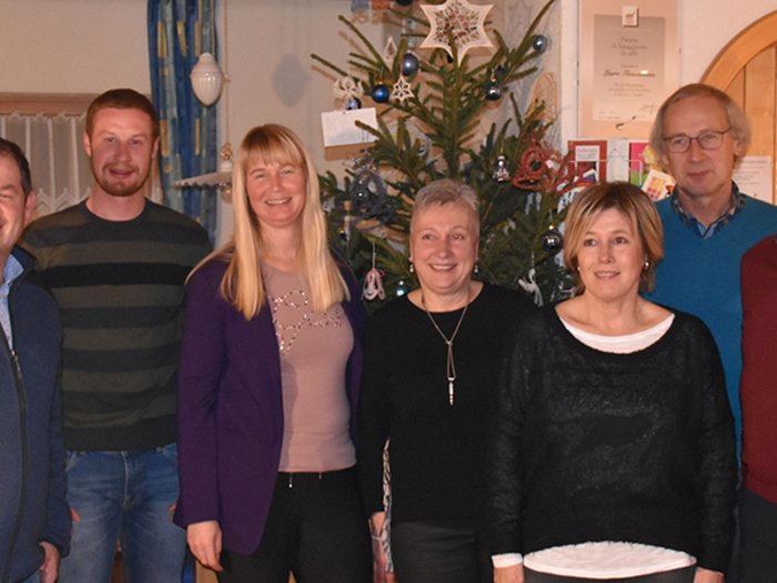 Solides Handwerk in Martell Gruppe von sieben Personen steht vor einem Weihnachtsbaum in einem Raum
