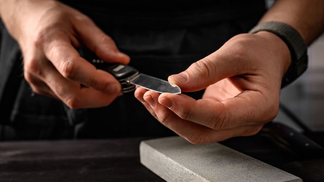 Home Uomo affila coltello pieghevole su pietra per affilare