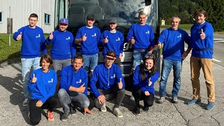 News Gruppe von 11 Personen in blauen Pullovern vor einem Reisebus zeigen Daumen hoch