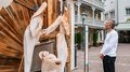 IDEA UNIKA 2025: 6ª edizione della Biennale d’arte nei centri dei paesi della Val Gardena Uomo osserva una natività in legno con figure in una strada cittadina