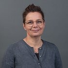 Fioristi Ritratto di donna sorridente con occhiali e capelli corti su sfondo grigio