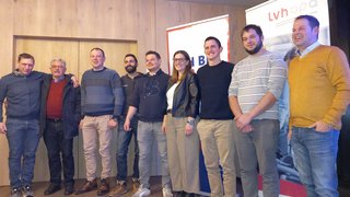 News Gruppenfoto mit neun lächelnden Personen vor Holzwand und Bannern