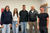 Cinque persone sorridenti posano insieme per una foto di gruppo in una stanza