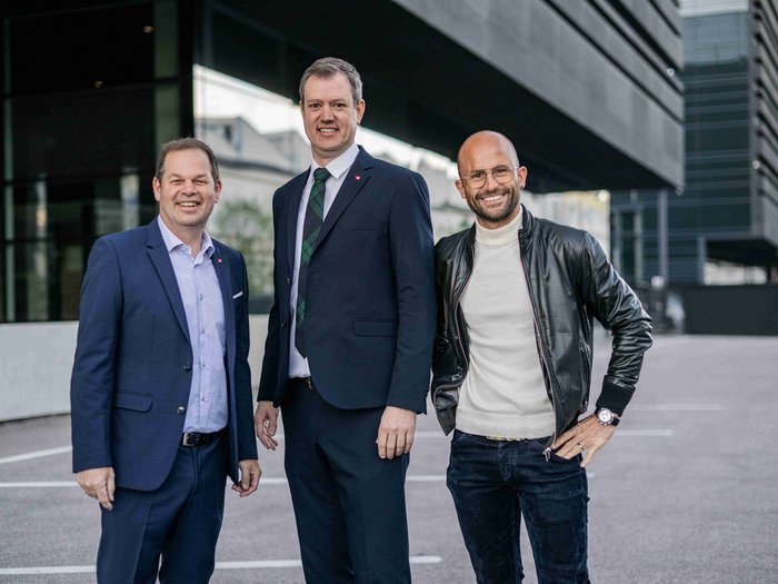 lvh: Kontinuität großgeschrieben Drei Männer, zwei in Anzügen und einer in Lederjacke, vor modernem Gebäude