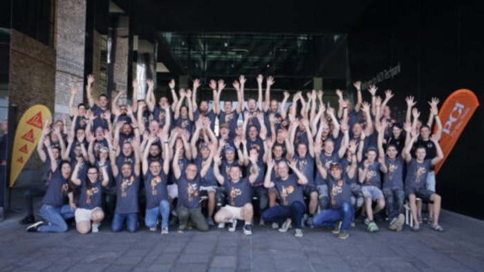 Südtirol begeistert beim Wettkampf der Fliesenleger/innen in Bozen! Gruppenfoto von Menschen mit erhobenen Händen vor einem Gebäude