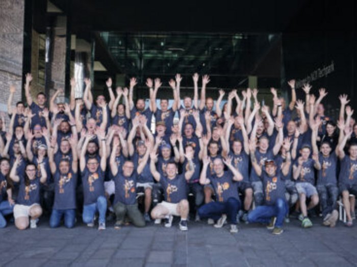 Südtirol begeistert beim Wettkampf der Fliesenleger/innen in Bozen! Gruppenfoto von Menschen mit erhobenen Händen vor einem Gebäude
