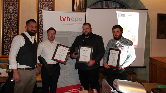 Junges Metzgerhandwerk im Rampenlicht Vier Männer bei Urkundenübergabe von LVH APA in einem Veranstaltungsraum