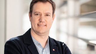 News Porträt eines Mannes mit verschränkten Armen in einem modernen Büro