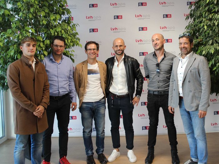 Kaminkehrer/innen: Die Zukunft im Blick Sechs Männer stehen vor einer LVH APA-Fotowand mit Pflanzen daneben