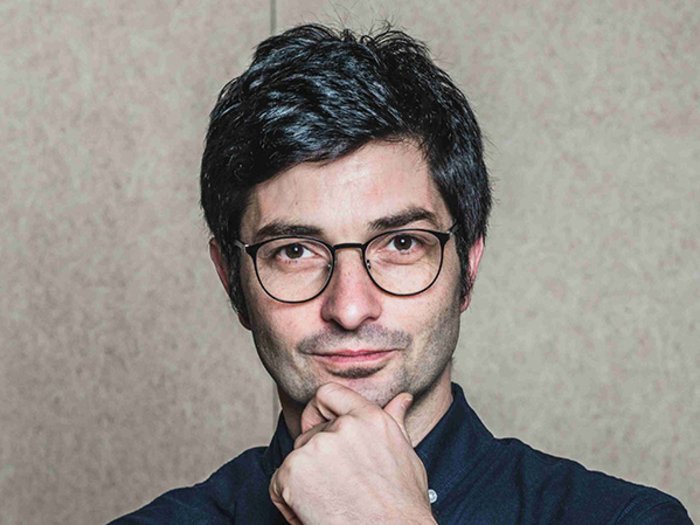 Zwei Südtiroler Projekte mit German Design Award ausgezeichnet Junger Mann mit Brille und dunklem Haar vor neutralem Hintergrund