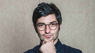 News Junger Mann mit Brille und dunklem Haar vor neutralem Hintergrund