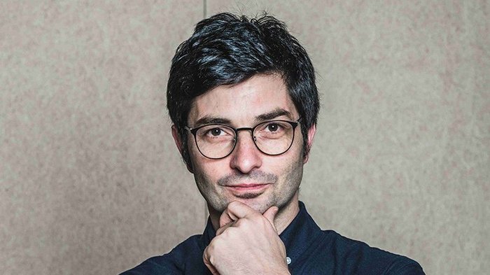 Zwei Südtiroler Projekte mit German Design Award ausgezeichnet Junger Mann mit Brille und dunklem Haar vor neutralem Hintergrund