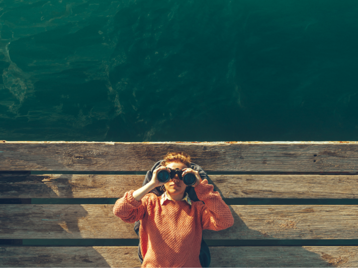 Incentivi innovativi e allo sviluppo di prodotti Persona su passerella di legno guarda l'acqua con binocolo