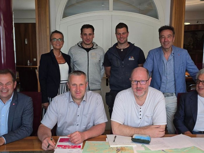 Mehr Raum für Betriebe: Sarntal arbeitet an neuen Gewerbezonen Acht Personen in einem Raum, vier sitzen an einem Tisch mit Papieren, vier stehen dahinter