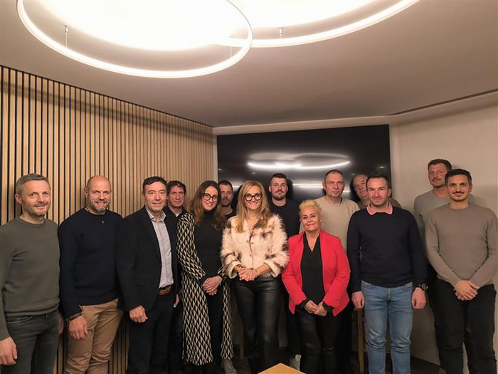 Ortsversammlung Feldthurns: Engagement vor Ort und klare Perspektiven Gruppenfoto von 14 Personen in einem modernen Raum mit Holzvertäfelung und Deckenleuchten