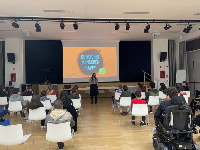 Die Welt der praktischen Berufe entdecken Donna tiene presentazione davanti a studenti seduti in aula con proiezione