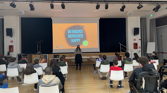 Die Welt der praktischen Berufe entdecken Frau hält Vortrag vor sitzenden Schülern in einem Saal mit Präsentation