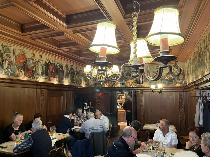 Althandwerker/innen unterwegs: Rundfahrt Weinviertel Gäste sitzen in einem traditionellen Gastraum mit Holzverkleidung und Wandmalereien