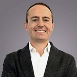 Das lvh-Team Porträt eines lächelnden Mannes mit weißem Hemd und dunklem Sakko vor grauem Hintergrund