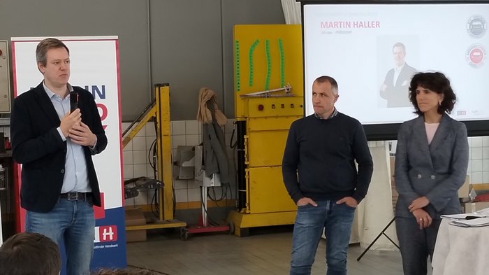 Punkteführerschein: Übergabe Unterschriften Drei Personen bei einer Präsentation in einer Werkstatt mit Publikumsbeteiligung