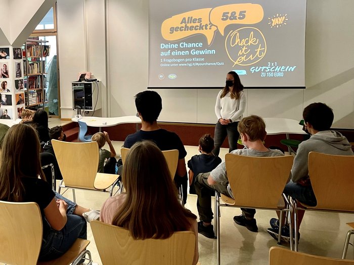 Praktische Berufe: Jugendlichen stehen viele Türen offen Schülerin präsentiert vor Klasse, Text über Gewinnchance und Gutschein auf Leinwand