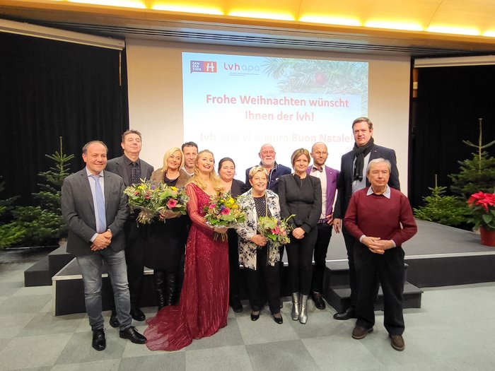 Il Concerto di Natale 2023 dell’apa: una serata magica Foto di gruppo a festa di Natale con mazzi di fiori e proiezione sullo sfondo