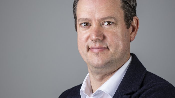Digitalisierungsschub für Kleinstbetriebe Porträt eines Mannes mit blauem Jackett und weißem Hemd vor grauem Hintergrund