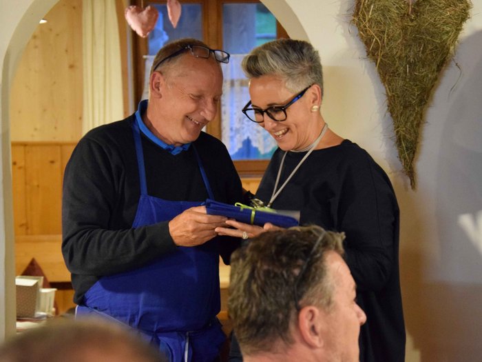 Senso di appartenenza e tradizione per i conciatetti Uomo con grembiule blu consegna un regalo ridendo a una donna