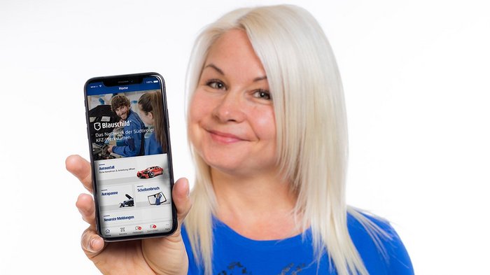 Blauschild – Die neue App für die Südtiroler Autofahrer Frau hält Smartphone mit Blauschild-App und lächelt