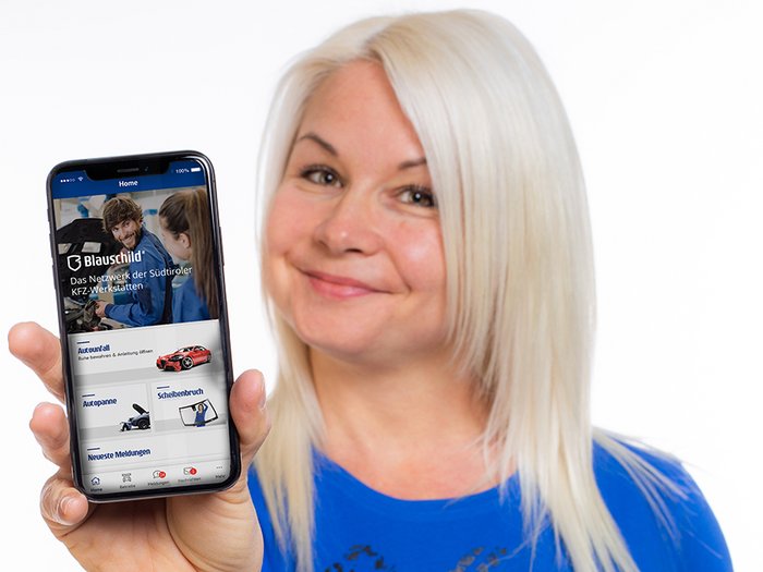 Blauschild – Die neue App für die Südtiroler Autofahrer Frau hält Smartphone mit Blauschild-App und lächelt