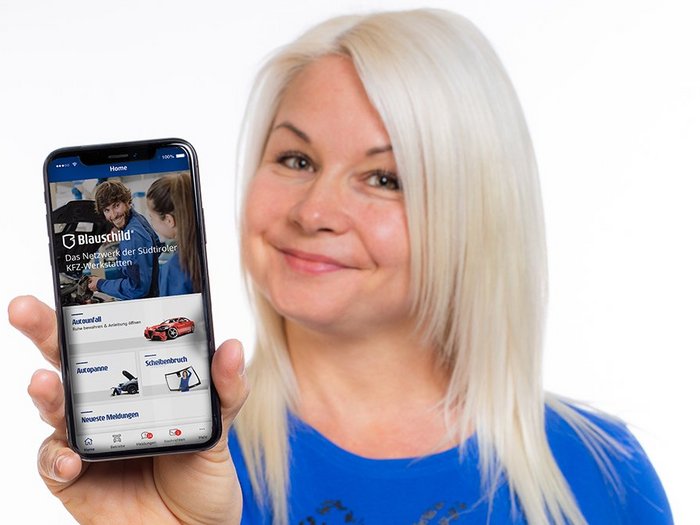 Blauschild – Die neue App für die Südtiroler Autofahrer Frau hält Smartphone mit Blauschild-App und lächelt