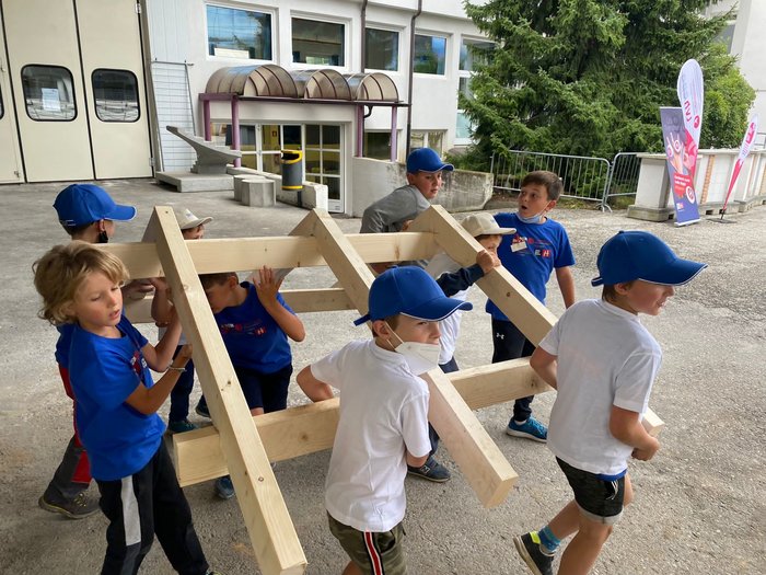 Neue Auflage der Kids-Akademie 2022 Kinder heben gemeinsam ein großes Holzgestell im Freien