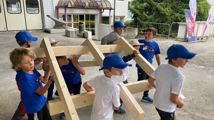Neue Auflage der Kids-Akademie 2022 Kinder heben gemeinsam ein großes Holzgestell im Freien