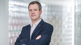 News Geschäftsmann in Anzug steht mit verschränkten Armen vor glasigem Hintergrund