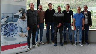 News Gruppenfoto von acht Männern vor Fenster mit Rollup des Wirtschaftsverbands Handwerk und Dienstleister