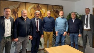 News Sieben Männer stehen nebeneinander in einem Büro mit Gemälde im Hintergrund