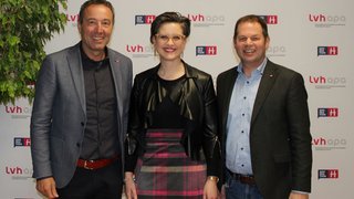 News Drei lächelnde Personen vor lvh a p o Hintergrund stehen zusammen