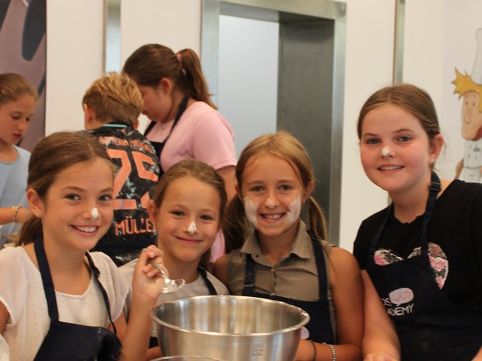 Backspaß und Kreativität – KidsAcademy backt in Kaltern Fröhliche Kinder backen gemeinsam mit Mehl im Gesicht und Küchenutensilien