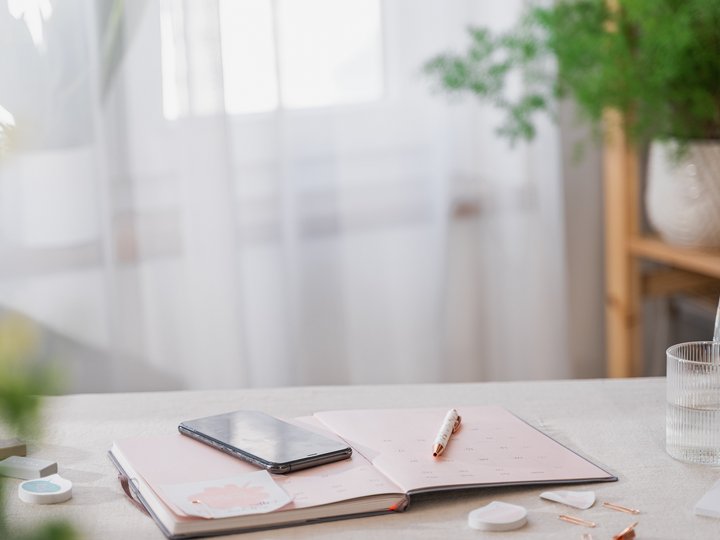 Artigianato sostenibile Smartphone su agenda aperta su tavolo accanto a bicchiere d'acqua e piante
