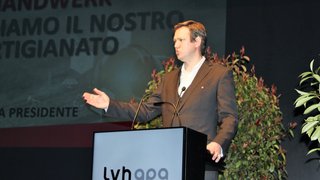 News Uomo parla al microfono durante conferenza con logo lvhapa e piante